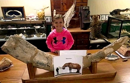 A young explorer behind the mastodon tusk